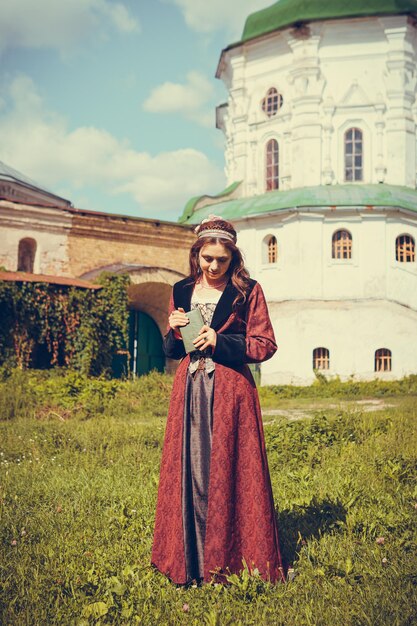 Portrait of brunette woman dressed in historical Baroque clothes with old fashion hairstyle outdoors