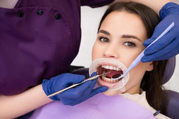 Portrait of brunette woman has checkup of teeth in denstist clinic