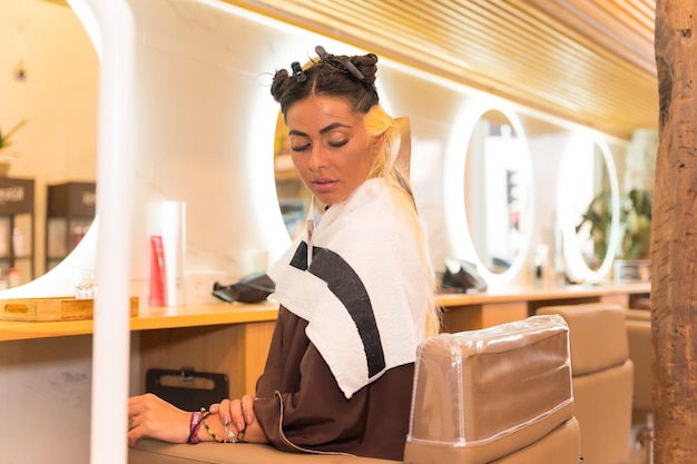 Portrait of a brunette woman sitting in the beauty salon hairdresser applying a blonde dye