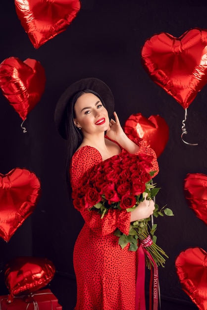 Portrait of a brunette woman with a large bouquet of red roses on a background