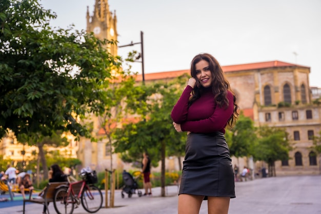 Ritratto di una donna bruna con una gonna di pelle accanto a una chiesa che visita lo stile di vita della città