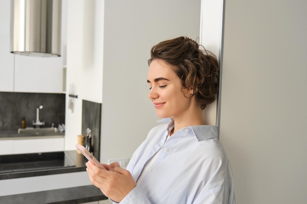 Photo portrait of brunette woman with smartphone sending message checking her mobile application ordering