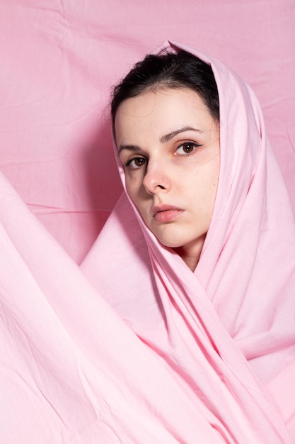 portrait of brunette woman wrapped in pink cloth pink background High quality photo