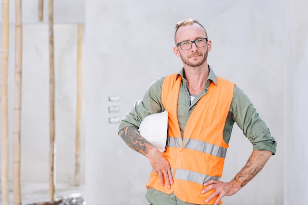 Photo portrait builder professional engineer architect foreman hipster worker work in construction site looking camera confident