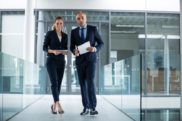 Portrait of business colleagues standing with digital tablet in corridor