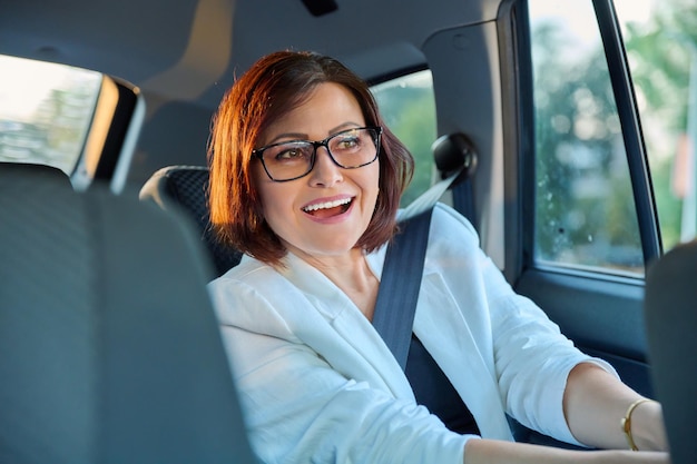 Photo portrait of business elegant middleaged woman in car in back passenger seat