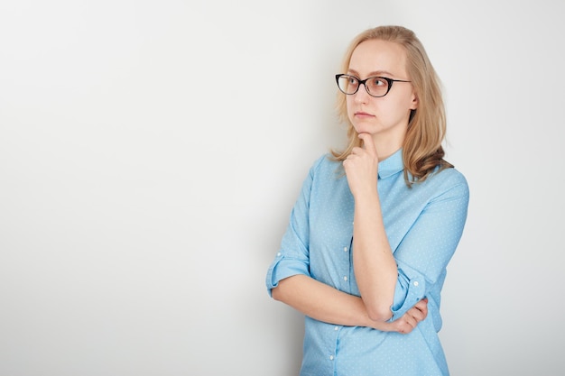 Portrait of business girl on a white background in a blue shirt and glasses