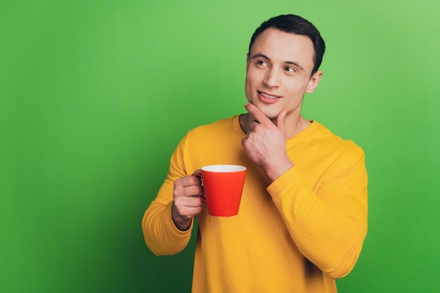 Portrait of business man guy drink coffee think look up empty space on green background