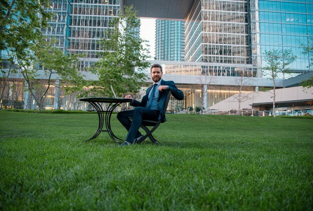 Portrait of business man sitting on modern outdoor working place successful business background of t