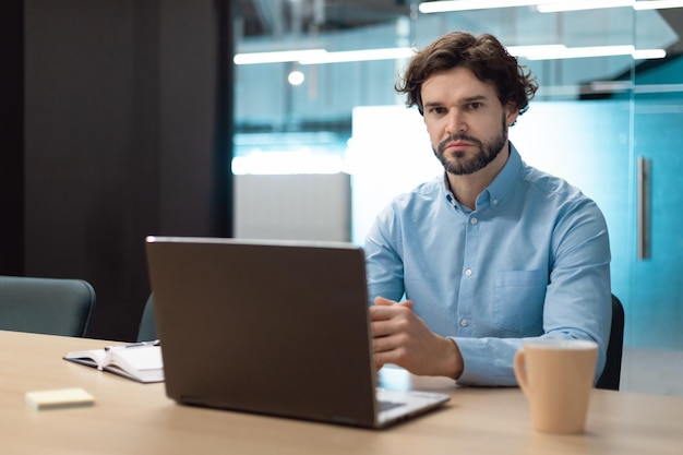 Portrait of business man using laptop and posing