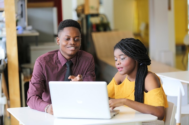 Portrait of business man and woman using laptop while sitting on table