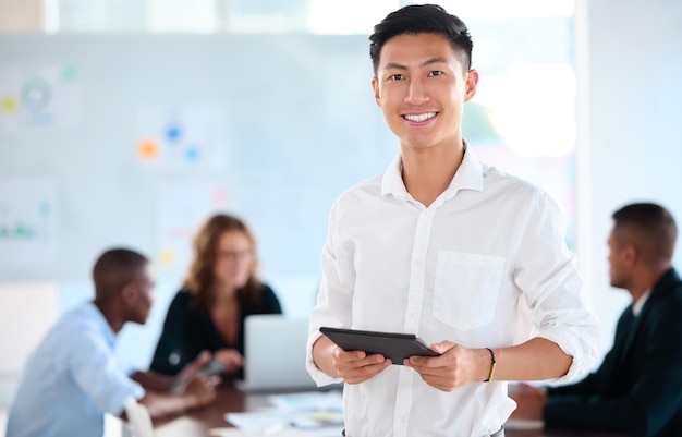 Portrait of business man working on tablet in office planning with team in meeting and management of corporate teamwork seminar Happy manager or worker in communication on technology at company