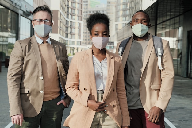 Portrait of business people in protective masks looking at camera while standing in the city