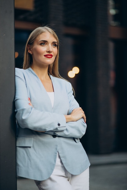 portrait of business woman in blue jacket standing by the wall
