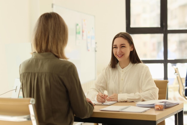 Portrait of business woman communicating with client and making notes in notepad in office hr