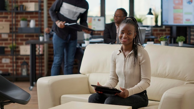 Портрет деловой женщины, сидящей на диване для работы на цифровом планшете, использующей технологии для финансового развития. Сотрудник компании, работающий с интернетом онлайн на устройстве.
