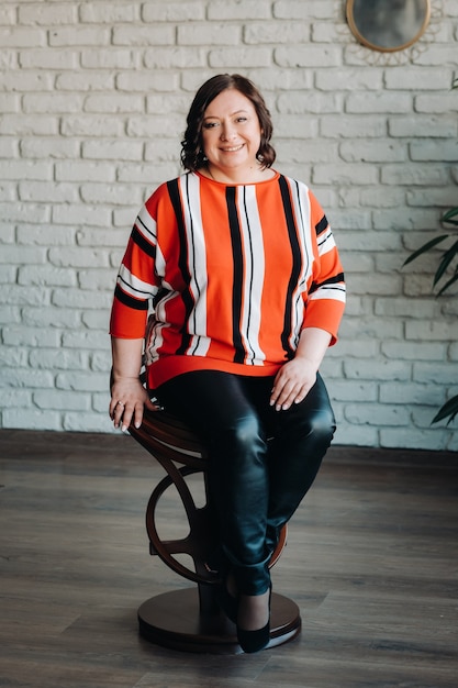 Portrait of a business woman in a striped jacket sitting on a sofa in the interior.