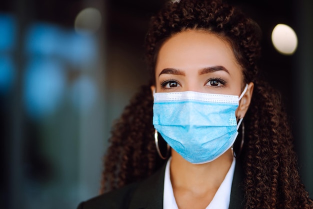 Ritratto di una donna d'affari che indossa una maschera protettiva e guarda a porte chiuse