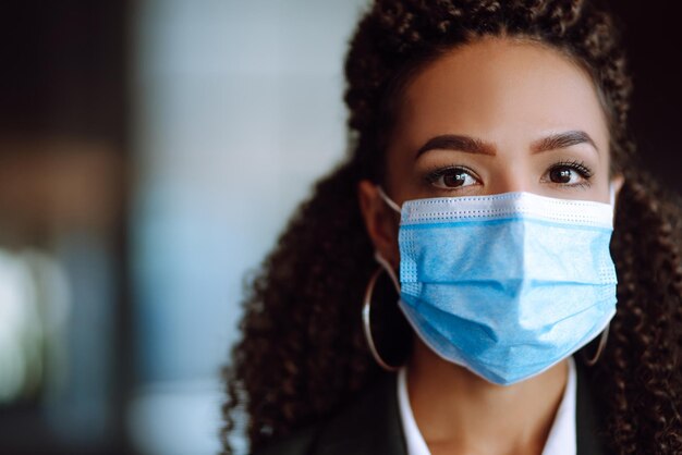 Portrait of a business woman wearing a protective mask and looking in camera