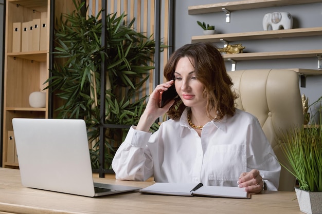 Portrait of a business woman in a white blouse at desk