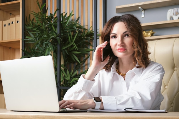 Portrait of a business woman in a white blouse at desk