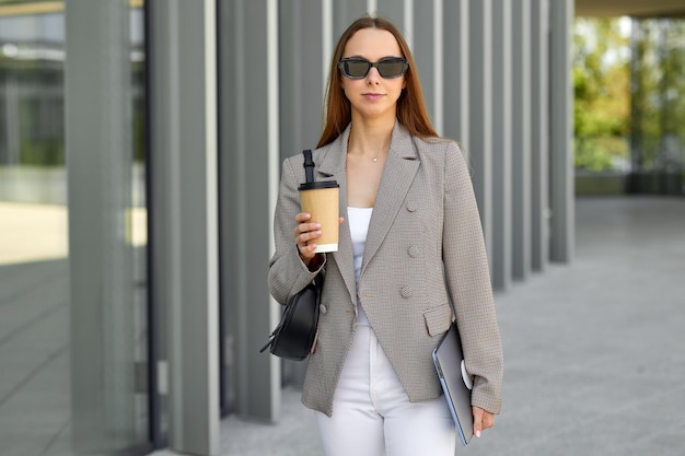 Photo portrait of a business woman with a cup of coffee in her hands against the background of a modern business center morning before work