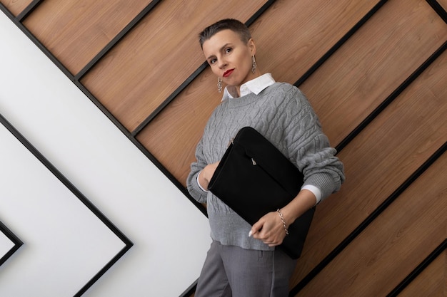 Portrait of a business woman with a folder for documents on the background of the office wall