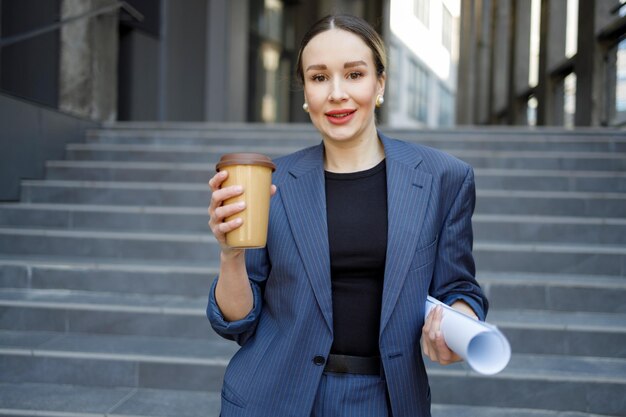 Portrait of business woman with rolled up paper outdoors