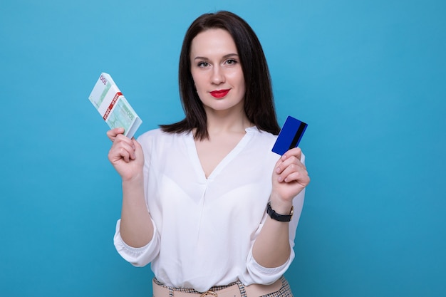 Ritratto di una donna d'affari con una mazzetta di soldi e una carta di credito su sfondo blu