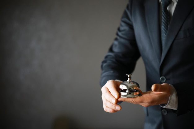 Portrait of Businessman in Black Suit Holding silver Bell Ring for Service Concept