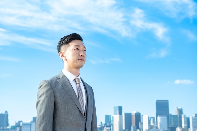 Portrait of a businessman, blue sky and buildings of big city