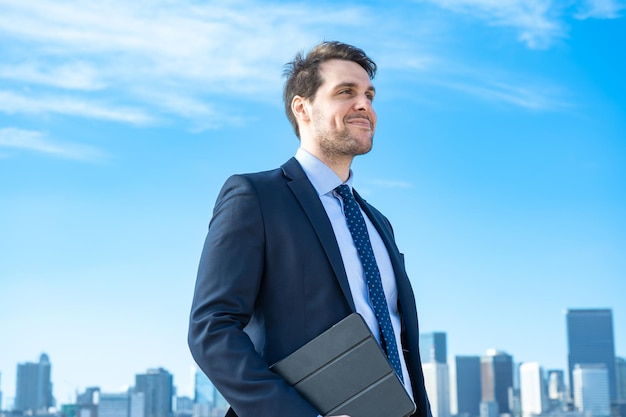 Portrait of a businessman, blue sky and buildings of big city