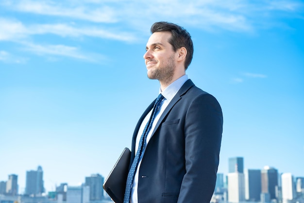 Portrait of a businessman, blue sky and buildings of big city