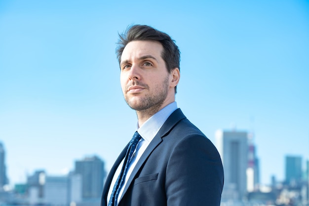 Portrait of a businessman, blue sky and buildings of big city