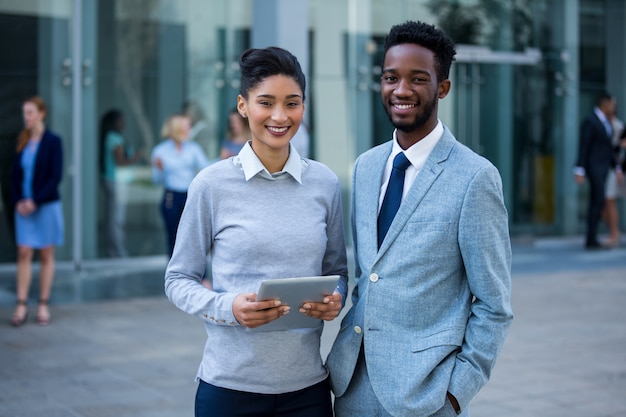 Portrait of businessman and colleague holding digital tablet