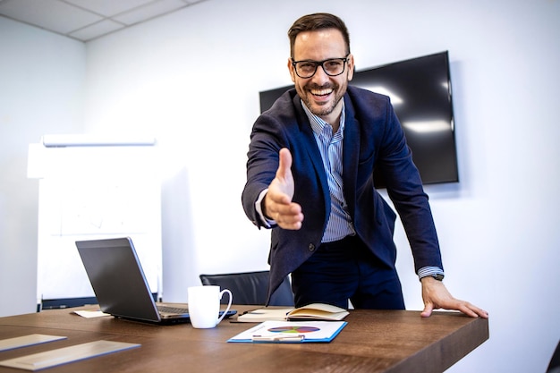 Portrait of businessman in elegant suit showing welcoming hand to the new employees