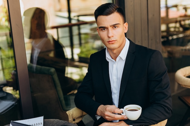 Portrait of businessman holding a cup of coffe and looking at the camera - Image