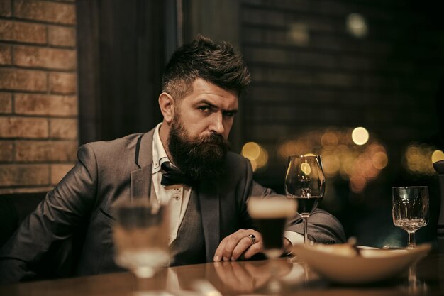 Portrait of a businessman holding glass of champagne over bar background and looking at camera