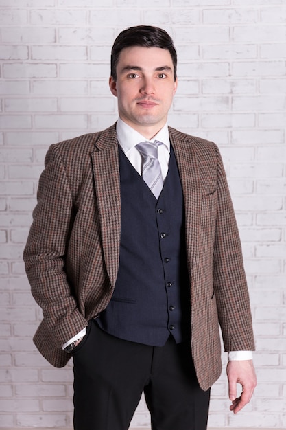 Photo portrait of businessman posing over white brick wall