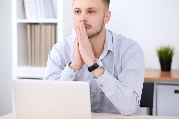 Portrait of businessman sitting at the desk in office workplace.