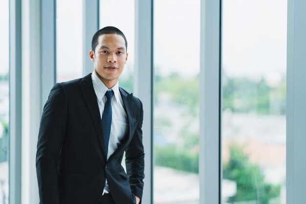 Photo portrait of businessman standing against window at office