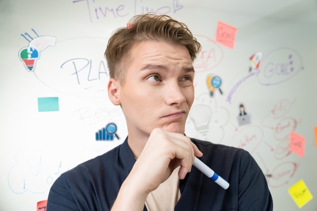 Portrait of businessman thinking while standing in front of board Immaculate