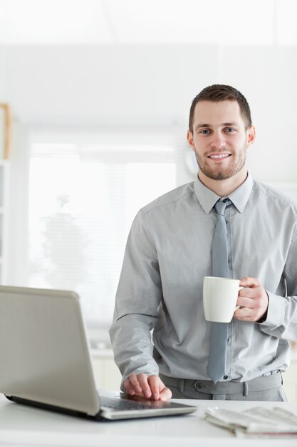 Ritratto di un uomo d'affari utilizzando un notebook mentre si beve il caffè