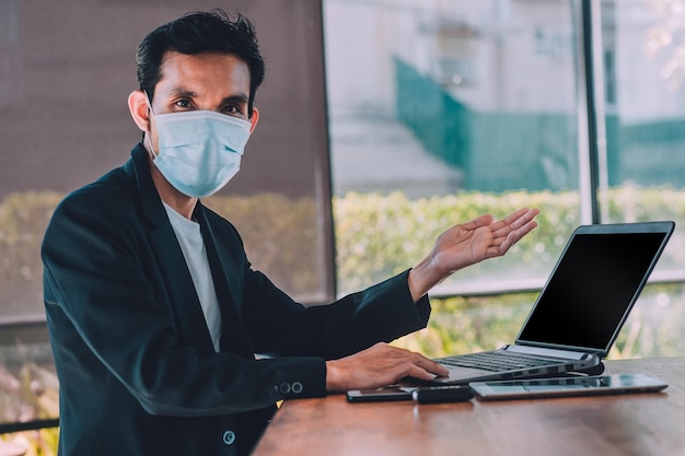 Photo portrait of businessman wearing mask sitting at office