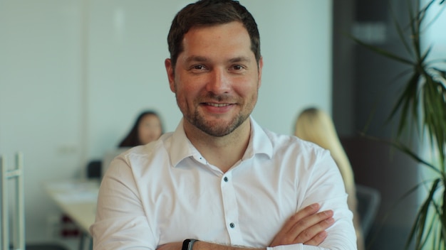 Portrait of businessman with arms crossed in office handsome young businessman smiling in the office business success people concept