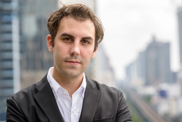 Portrait of businessman with brown hair wearing suit against view of the city