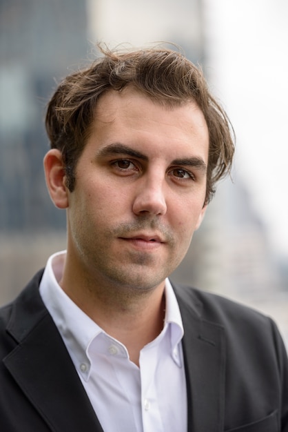 Portrait of businessman with brown hair wearing suit against view of the city