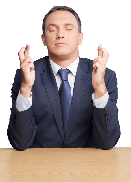 portrait of a businessman with eyes closed and fingers crossed