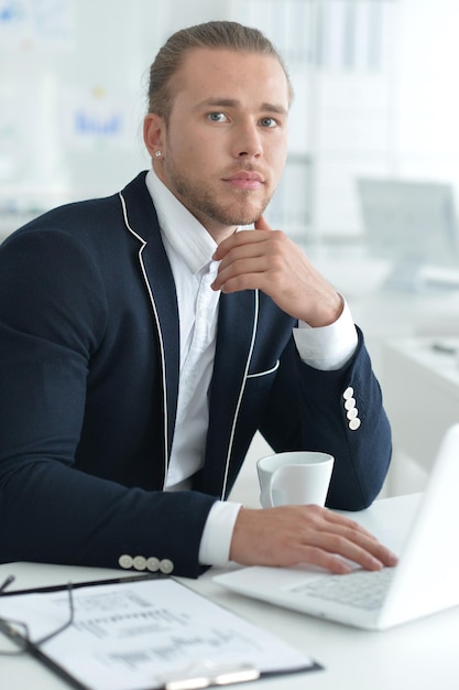 Portrait of businessman working at table with laptop