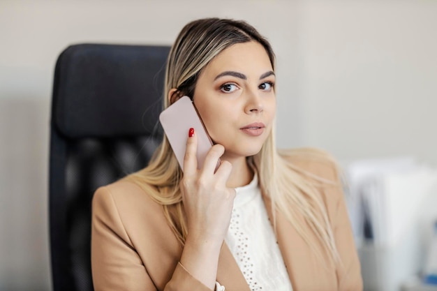 Портрет деловой женщины, разговаривающей по телефону в офисе